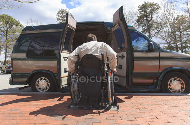 Человек с травмой спинного мозга садится в свой фургон — стоковое фото