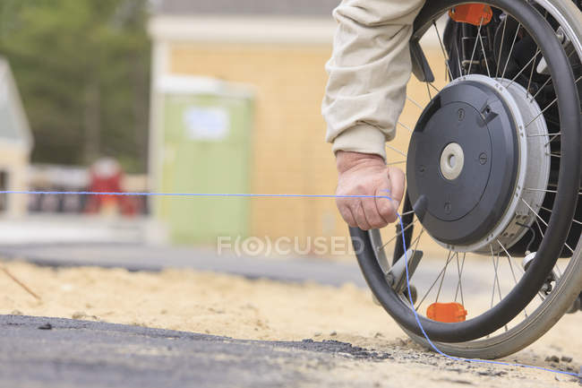 Руководитель строительства с травмой спинного мозга тянет мел на краю тротуара — стоковое фото