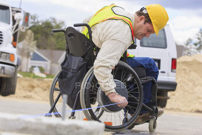 Construction supervisor with Spinal Cord Injury pulling chalkline at edge of pavement — Stock Photo