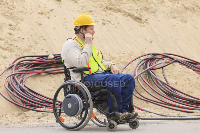 Construction supervisor with Spinal Cord Injury on walkie talkie with underground utility cables — Stock Photo