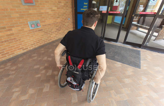 Человек с повреждением спинного мозга входит в электронную дверь — стоковое фото