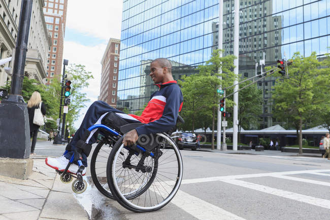 Homme en fauteuil roulant qui a eu une méningite rachidienne sur un trottoir — Photo de stock