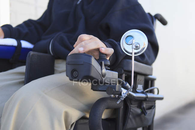 Hombre con lesión medular usando su silla de ruedas motorizada - foto de stock
