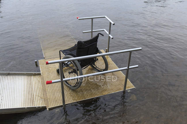 Wheelchair on a dock at a lake, high angle view — Stock Photo