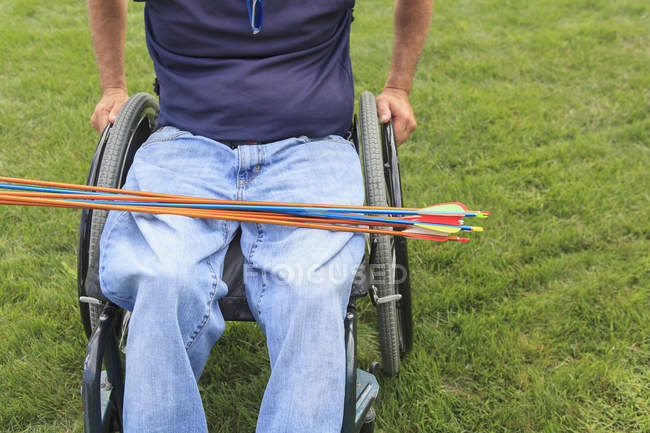 Homme avec blessure de la moelle épinière en fauteuil roulant se préparant pour la pratique du tir à l'arc — Photo de stock