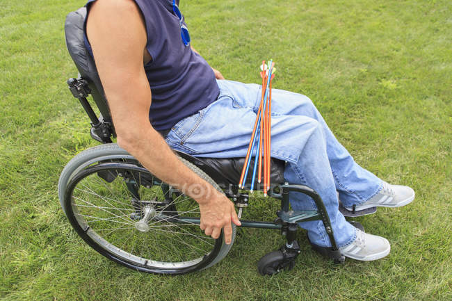 Mann mit Querschnittslähmung im Rollstuhl bereitet sich auf Bogenschießen vor — Stockfoto