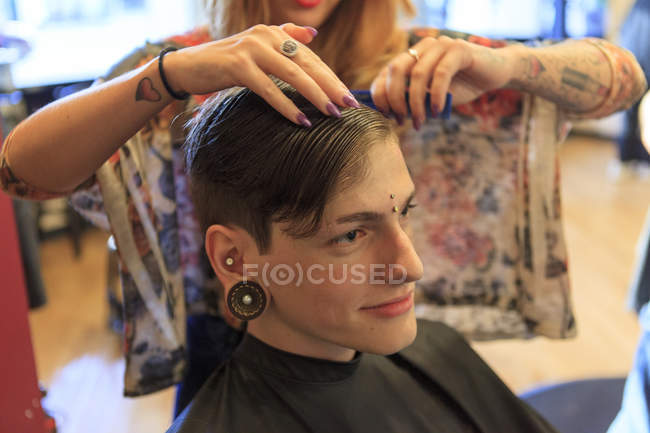 Hombre de moda con una lesión en la médula espinal en una peluquería que se corta el pelo - foto de stock