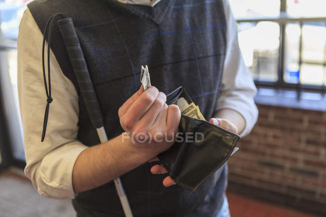 Young blind man with cane counting his money — Stock Photo
