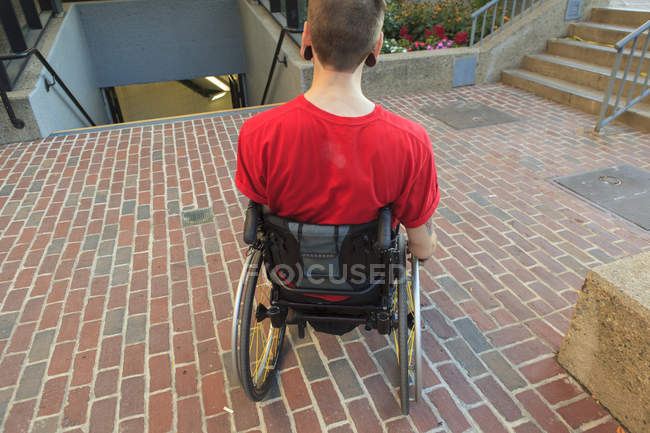 Uomo alla moda con una lesione del midollo spinale in sedia a rotelle pianificazione il suo accesso alla metropolitana — Foto stock