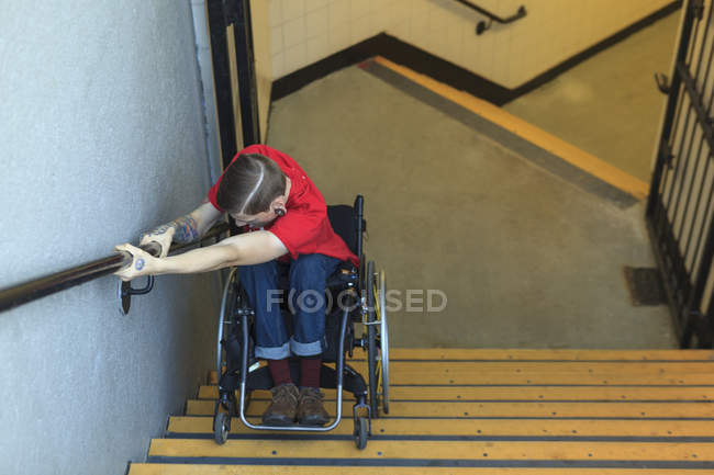 Trendy man with a spinal cord injury in wheelchair going down subway stairs backwards — Stock Photo