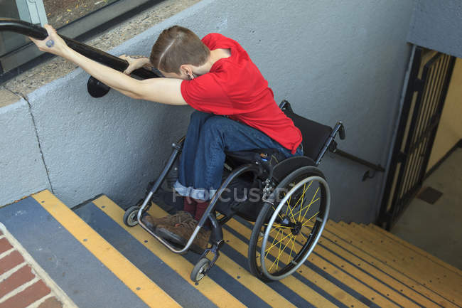 Homem na moda com uma lesão na medula espinhal em cadeira de rodas descendo escadas do metrô para trás — Fotografia de Stock
