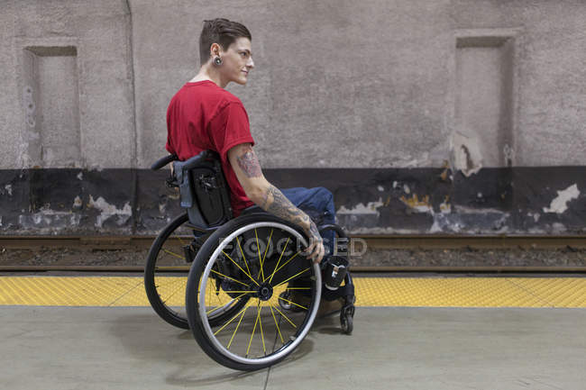 Модний чоловік з травмою спинного мозку в інвалідному візку чекає на поїзд метро — стокове фото