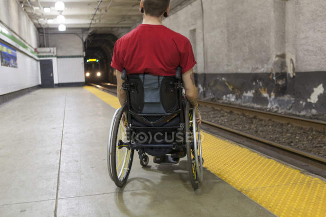 Homem na moda com uma lesão na medula espinhal em cadeira de rodas à espera de um trem de metrô — Fotografia de Stock