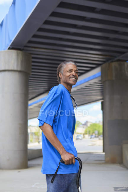 Hombre con lesión cerebral traumática dando un paseo por debajo de un puente de la ciudad - foto de stock