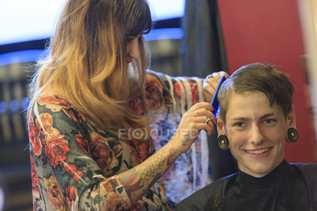 Модный мужчина с травмой спинного мозга в парикмахерской, стригущий волосы — стоковое фото