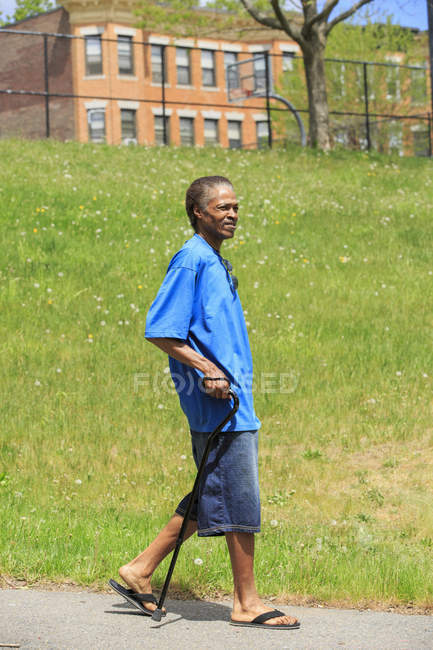 Hombre con lesión cerebral traumática dando un paseo con su bastón - foto de stock