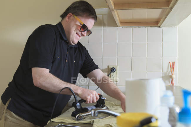 Homem com cegueira congênita passando a camisa em casa — Fotografia de Stock
