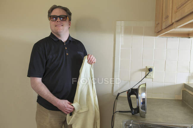 Mann mit angeborener Blindheit bügelt sein Hemd zu Hause — Stockfoto