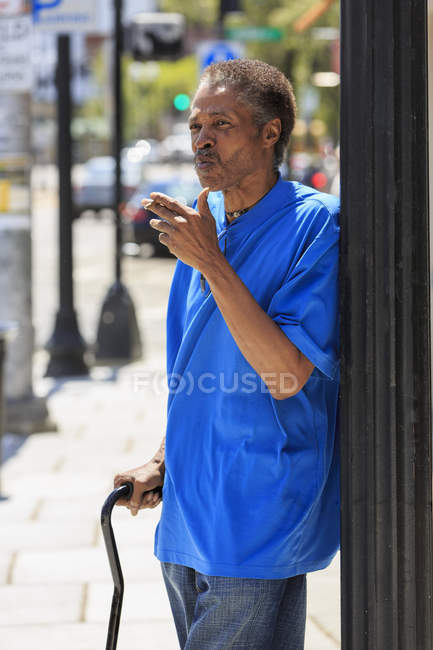Man with Traumatic Brain Injury with cane smoking on the street — Stock Photo
