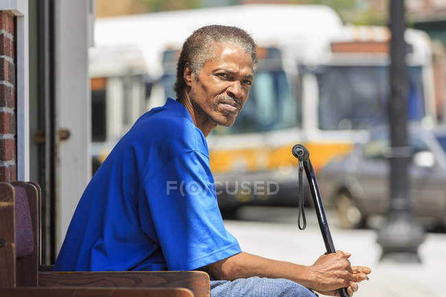 Man with Traumatic Brain Injury relaxing with his cane near the bus station — Stock Photo