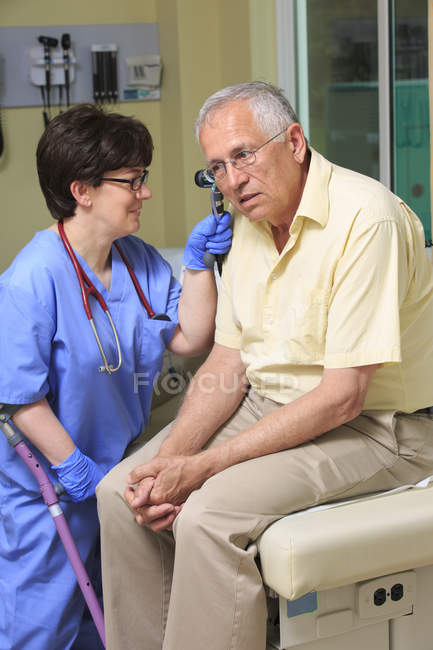 Nurse with Cerebral Palsy checking the ears of a patient in a clinic — Stock Photo