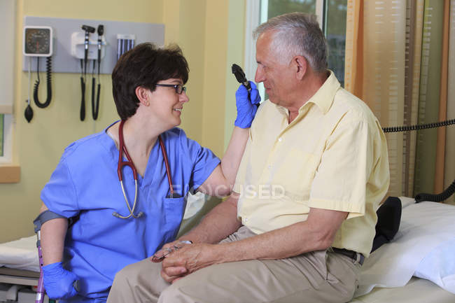 Nurse with Cerebral Palsy checking a patient's eyes in a clinic — Stock Photo