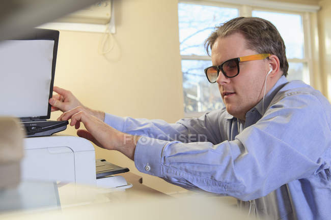 Hombre con ceguera congénita escaneando papeleo en su computadora - foto de stock