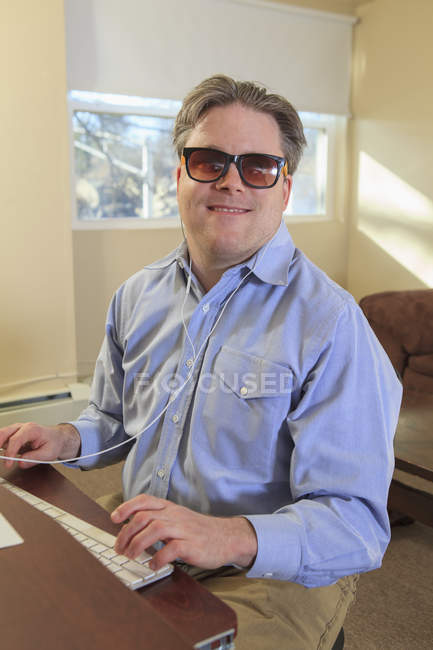 Людина з вродженою сліпотою, використовуючи допоміжні технології на своєму комп'ютері, щоб слухати — стокове фото