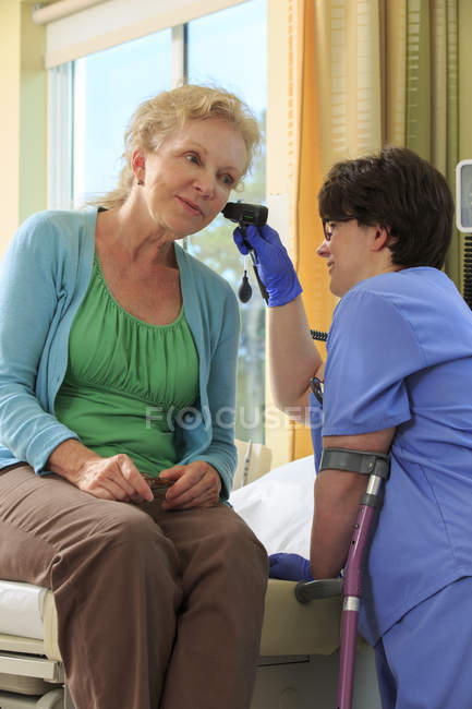 Nurse with Cerebral Palsy checking the ears of a patient in a clinic — Stock Photo