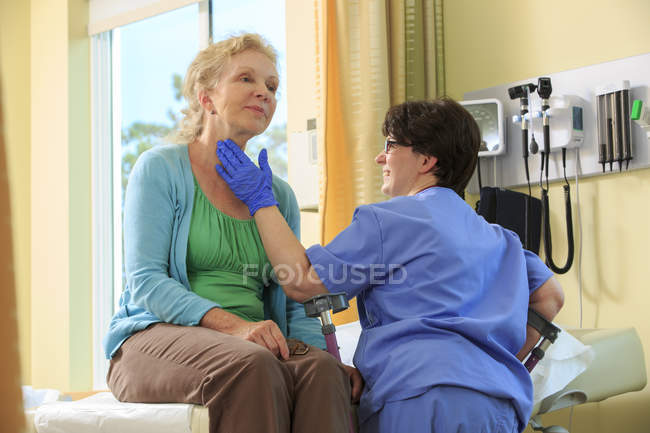 Nurse with Cerebral Palsy checking a patient's thyroid in a clinic — Stock Photo