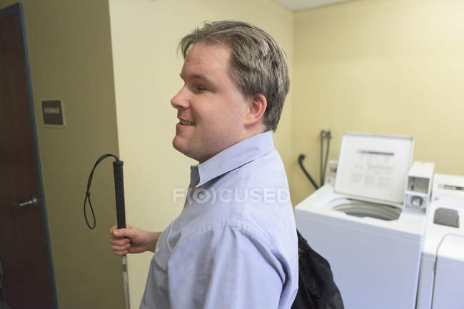Man with congenital blindness leaving the laundry room with his laundry — Stock Photo