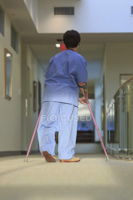 Nurse with Cerebral Palsy walking down the hallway of a clinic with her canes — Stock Photo