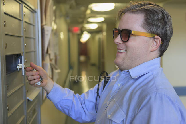 Man with congenital blindness opening his mailbox in his apartment building — Stock Photo