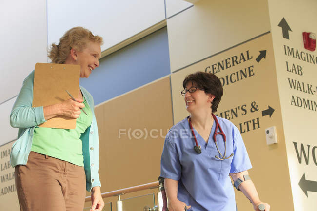 Infirmière avec paralysie cérébrale marchant dans le couloir d'une clinique avec un administrateur — Photo de stock