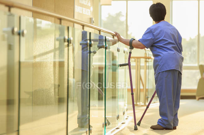 Enfermera con parálisis cerebral de pie en el pasillo de una clínica - foto de stock