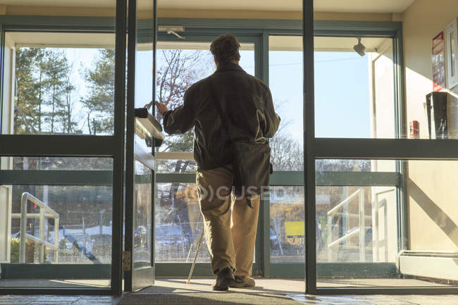 Hombre con ceguera congénita saliendo de su edificio de apartamentos - foto de stock