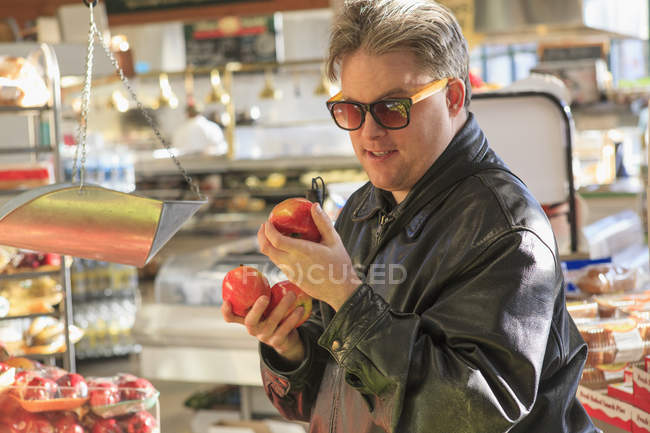 Hombre con ceguera congénita en el supermercado recogiendo fruta - foto de stock