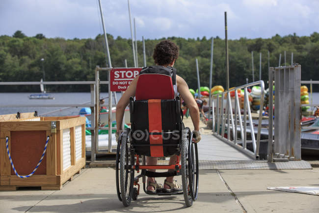 Femme avec une blessure à la moelle épinière dans un fauteuil roulant sur un quai de bateau — Photo de stock