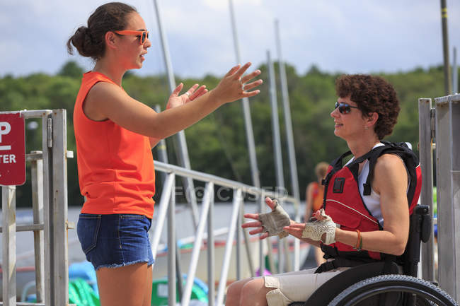 Женщина с травмой спинного мозга разговаривает с инструктором об использовании каяка — стоковое фото