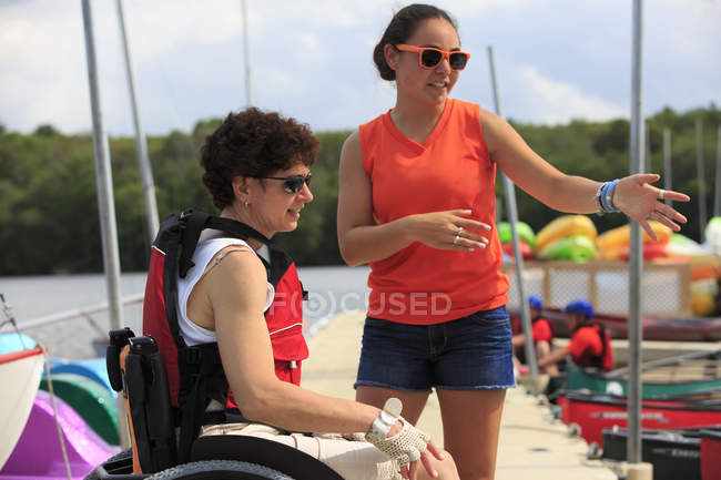 Mujer con una lesión en la médula espinal hablando con un instructor sobre el uso de un kayak - foto de stock