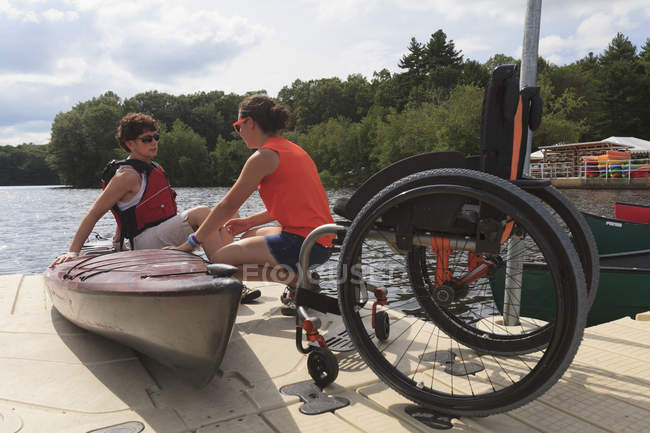 Instructeur aidant une femme atteinte d'une lésion médullaire à utiliser un kayak — Photo de stock