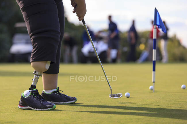 Женщина с протезом ноги в гольф положить зеленый — стоковое фото