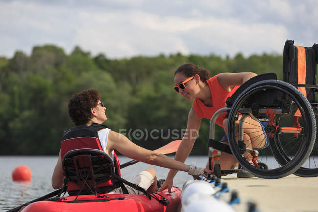 Un instructeur aide une femme blessée à la moelle épinière à utiliser un kayak — Photo de stock