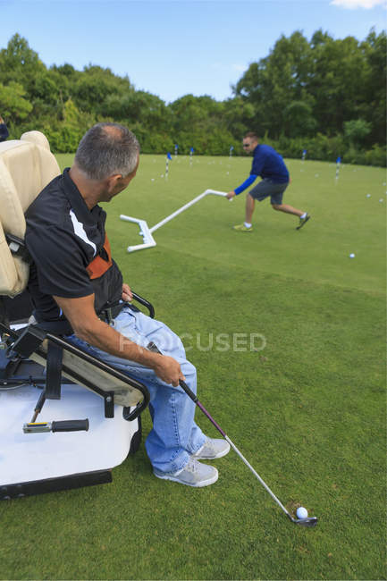 Людина з травмою спинного мозку в адаптивному візку в гольфі покласти зеленого — стокове фото