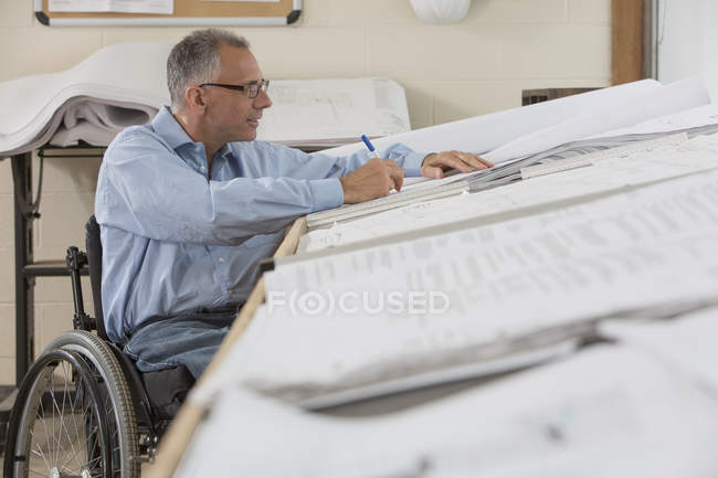 Engenheiro de projecto com uma lesão na coluna vertebral numa cadeira de rodas a trabalhar em desenhos — Fotografia de Stock