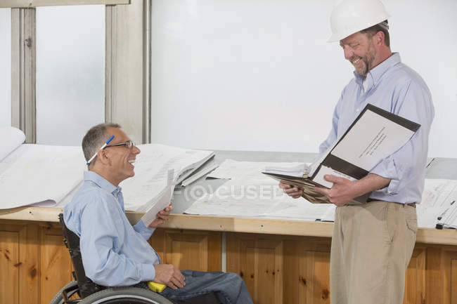 Deux ingénieurs de projet parlent du travail, un dans un fauteuil roulant avec une blessure à la moelle épinière — Photo de stock