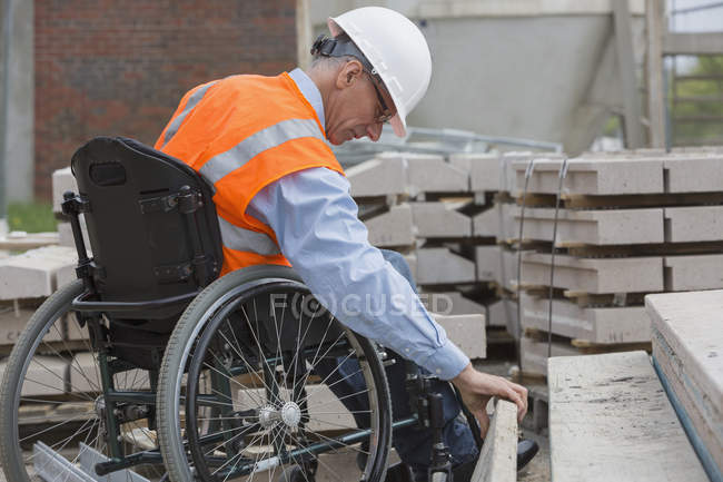 Ingénieur de projet avec une blessure à la moelle épinière dans un fauteuil roulant sur le chantier — Photo de stock