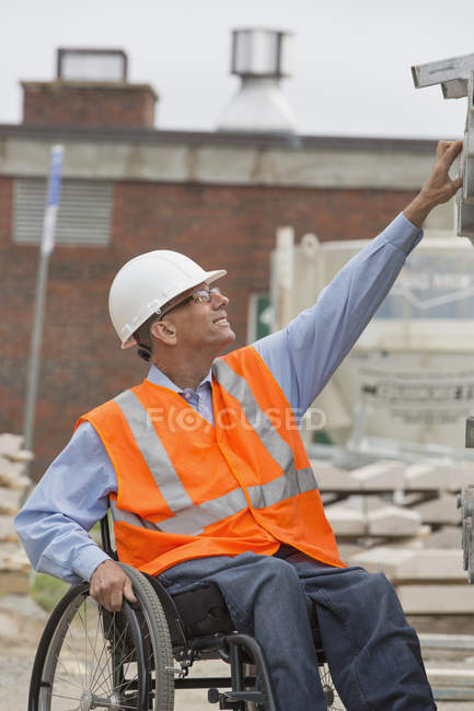 Ingénieur de projet avec une blessure à la moelle épinière dans un fauteuil roulant sur le chantier — Photo de stock