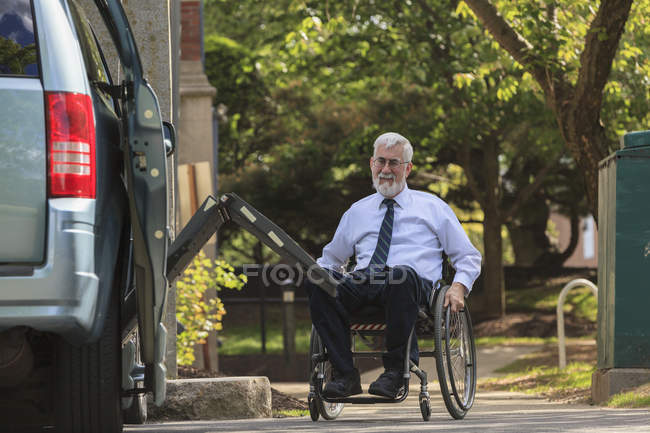 Businessman with Muscular Dystrophy in a wheelchair entering his accessible van in the parking lot — Stock Photo