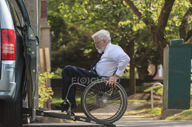 Uomo d'affari con distrofia muscolare in sedia a rotelle che entra nel suo furgone accessibile nel parcheggio — Foto stock